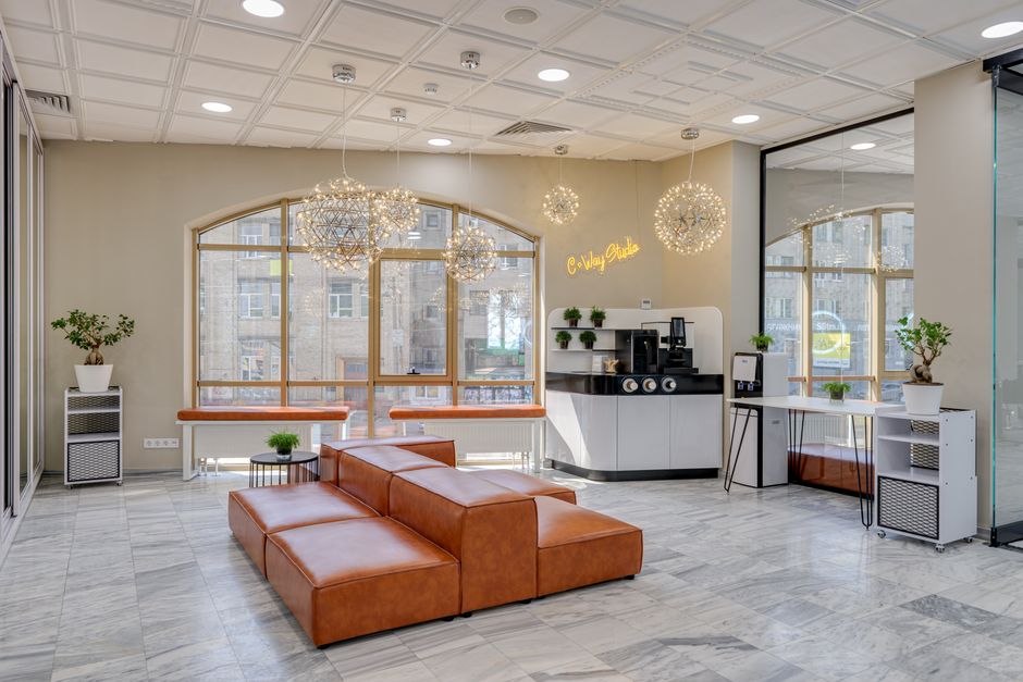 Spacious modern office lobby featuring leather seating, a coffee station, and elegant lighting.